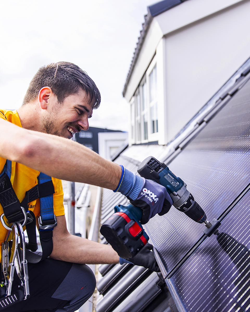 SolarNRG monteur installeert zonnepanelen op een woonhuis