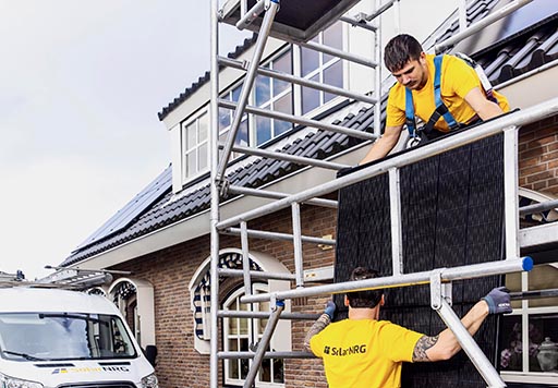 SolarNRG monteurs tillen een zonnepaneel het dak op
