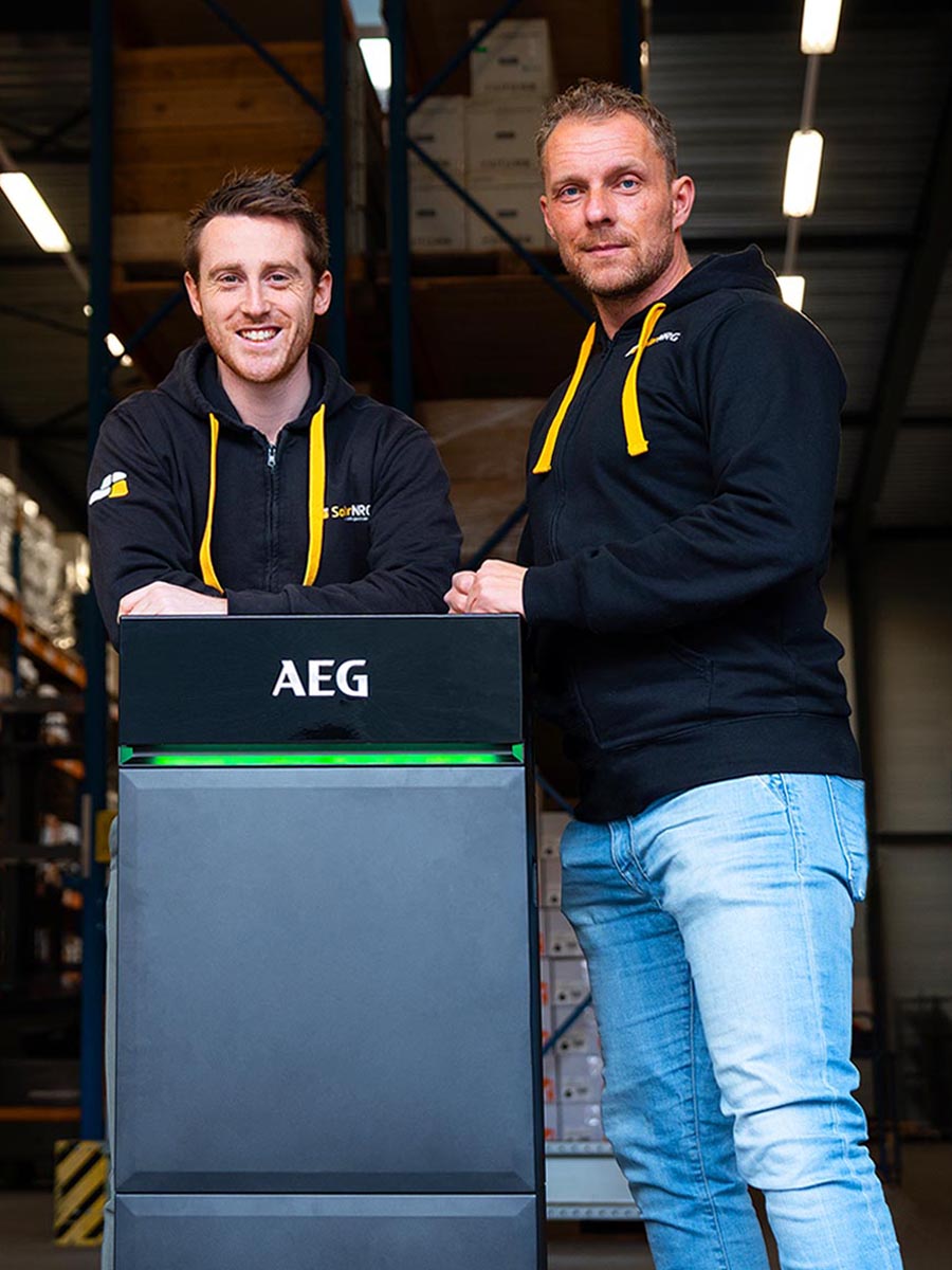 SolarNRG teamleden met een AEG thuisbatterij in ons magazijn in Poeldijk