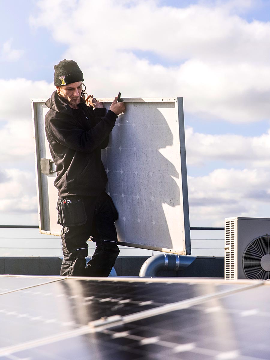 SolarNRG grootzakelijk onderhoud inspecteur draagt een zonnepaneel